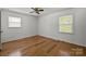 Empty bedroom features hardwood floors, a ceiling fan, and two windows that provide ample natural light at 6231 Coach Hill Ln, Charlotte, NC 28212