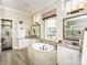 Bright bathroom featuring a bathtub, dual vanities, a shower, and exterior views at 6510 Honeymeade Cir, Charlotte, NC 28277