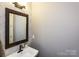 Clean powder room with a modern vanity, framed mirror, sleek faucet, and decorative wall paneling at 6510 Honeymeade Cir, Charlotte, NC 28277