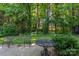 A beautiful backyard featuring a concrete patio with outdoor seating surrounded by lush green trees and landscaping at 9419 Olivia Ln, Charlotte, NC 28277