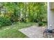 A beautiful backyard featuring a concrete patio with outdoor seating surrounded by lush green trees and landscaping at 9419 Olivia Ln, Charlotte, NC 28277