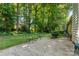 A beautiful backyard featuring a concrete patio with outdoor seating surrounded by lush green trees and landscaping at 9419 Olivia Ln, Charlotte, NC 28277