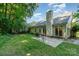 Exterior view of a home showcasing its siding, windows, chimney, lush backyard, and a concrete patio with seating at 9419 Olivia Ln, Charlotte, NC 28277