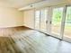 Open living room featuring a hardwood floor and access to a patio through three white glass doors at 9541 Shannon Green Dr # C, Charlotte, NC 28213