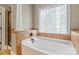 Modern bathroom with a tiled bathtub, glass block window, and ceramic tile at 1009 Jerry Ln, Matthews, NC 28105