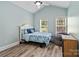 Well-lit bedroom with hardwood floors, light-blue walls, two windows, and a ceiling fan at 1009 Jerry Ln, Matthews, NC 28105