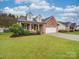 Traditional red brick home with a lush front lawn, inviting entrance, and attached two-car garage at 1209 Pressley Downs Se Dr, Concord, NC 28025