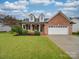 Charming brick home featuring a well-manicured lawn, two-car garage, and inviting front porch at 1209 Pressley Downs Se Dr, Concord, NC 28025