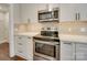 Stainless steel oven and microwave appliances are complemented by white cabinets and countertops at 1209 Pressley Downs Se Dr, Concord, NC 28025