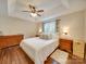 Cozy main bedroom features a tray ceiling, ceiling fan, and wood floors at 1209 Pressley Downs Se Dr, Concord, NC 28025