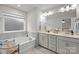 Bright bathroom featuring a tub, double vanity, large mirror, and stylish fixtures at 12205 Gambrell Dr, Charlotte, NC 28278
