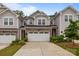 Charming townhome featuring a two-car garage, stone accents, and manicured landscaping at 12205 Gambrell Dr, Charlotte, NC 28278