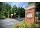 A welcoming gated entrance with brick pillars, signage, and lush greenery showcases community pride at 14979 Santa Lucia Dr # 2408, Charlotte, NC 28277
