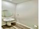 This powder room features a pedestal sink, round mirror, and wood-look flooring at 1510 Old Rivers Rd # 171, Concord, NC 28027