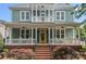 Charming two-story home with a welcoming front porch and yellow door flanked by lush landscaping at 15830 Waterfront Dr, Huntersville, NC 28078