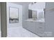 Modern bathroom featuring marble floors, gray cabinets with gold hardware, and large vanity mirror at 2413 Cross Country Rd, Charlotte, NC 28270