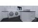 Well-organized laundry room featuring white cabinets, black countertop, washer, and dryer at 2413 Cross Country Rd, Charlotte, NC 28270