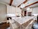 Bright kitchen features a large island with marble countertops, white cabinets, and wooden beams at 4025 Foxes Trl, Cramerton, NC 28032