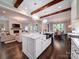 Open-concept kitchen with a marble island, wooden beams, and an adjoining living room and dining area at 4025 Foxes Trl, Cramerton, NC 28032