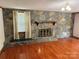Living room with a stone fireplace, wood mantel, wood-look floor, and a window with curtain at 6018 Unionville Rd, Monroe, NC 28110