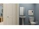 Modern powder room with a pedestal sink, mirror, toilet, and blue wall at 6295 Fairfax Ct, Maiden, NC 28650