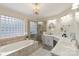 Bright bathroom featuring a soaking tub, glass shower, marble countertops, and elegant chandelier at 800 Isle Of Palms Ct, Fort Mill, SC 29708
