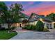 Stunning home featuring mature trees, lush landscaping, and a circular driveway against a colorful sky at dusk at 8813 Covey Rise Ct, Charlotte, NC 28226