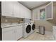 Laundry room features white cabinets, a sink, and a modern washer and dryer at 8813 Covey Rise Ct, Charlotte, NC 28226