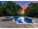 Stunning backyard pool with spa, lush landscaping, and a beautiful sunset backdrop, perfect for relaxation at 8813 Covey Rise Ct, Charlotte, NC 28226