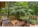 This wooden deck has chairs, plants, and a beautiful view of the green backyard at 8968 St Croix Ln, Charlotte, NC 28277