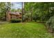 Lush green backyard with mature trees, wood paneled siding, and a charming outdoor area at 8968 St Croix Ln, Charlotte, NC 28277