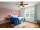 Inviting bedroom with a blue quilt bed, fan, large window, and pink accent wall, creating a cozy retreat at 943 Shinnville Rd, Mooresville, NC 28115