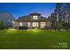 View of the landscaped backyard, featuring a brick home, manicured lawn, and mature trees at 9833 Ardley Park Way, Mint Hill, NC 28227