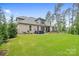 Spacious backyard with a brick house, lush green lawn, mature trees, and a hot tub at 9833 Ardley Park Way, Mint Hill, NC 28227