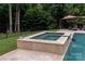 Close up of a travertine hot tub spilling into the pool in a beautifully landscaped backyard at 1032 Seminole Dr, Waxhaw, NC 28173
