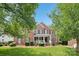 Charming two-story red brick home with a covered front porch and well-manicured lawn and mature trees at 11103 Fountaingrove Dr, Charlotte, NC 28262