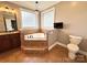 Bright bathroom featuring a tiled jacuzzi tub with glass-block windows and neutral decor at 141 Weathers Creek Rd, Troutman, NC 28166