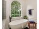 A luxury soaking tub sits below a large window that provides ample natural light and a view at 14831 Charterhouse Ln, Huntersville, NC 28078