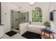 Luxurious bathroom with a soaking tub, a tiled shower with a glass enclosure and a large window offering natural light at 14831 Charterhouse Ln, Huntersville, NC 28078