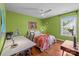 Green-walled bedroom with a desk, white ceiling fan, and a window, offering a bright and airy atmosphere at 2009 Waterbury Ln, Waxhaw, NC 28173