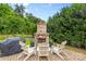 Outdoor brick fireplace with Adirondack chairs on a stone patio in a lush green backyard at 2010 Brightflower Ln, York, SC 29745