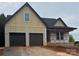 New construction exterior featuring a two-car garage and modern design with a covered porch, set in a gravel driveway at 2589 Polo Ln, Maiden, NC 28650