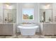 Bright bathroom with dual vanities, freestanding tub under window, and stylish lighting creating a spa-like retreat at 5127 Lansing Dr, Charlotte, NC 28270