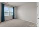 An empty bedroom with a large window with curtains and neutral walls and carpet at 5481 Comiskey Aly, Kannapolis, NC 28081