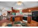 Eat-in kitchen with wood cabinets, black appliances, and a view into the living room with stone fireplace at 7232 Executive Cir, Denver, NC 28037