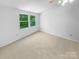 Neutral carpet and large windows offering green views make this empty bedroom a bright and comfortable retreat at 7737 Batavia Ln, Charlotte, NC 28213