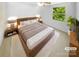 Serene bedroom with wood-frame bed, complemented by stylish nightstands, soft rug, and a large window at 7737 Batavia Ln, Charlotte, NC 28213