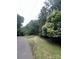 View of the heavily treed land available at this property. Paved street and gravel path visible at 7949 Ritter Dr, Charlotte, NC 28270