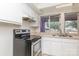 A kitchen showcasing white cabinets, an electric stove, and a double-basin sink with a window view at 10 Cedarvilla Dr, Rock Hill, SC 29730
