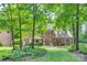 Stately two-story brick home featuring mature trees, lush landscaping, and a charming front garden at 10215 Balmoral Cir, Charlotte, NC 28210